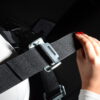 Sim racing harness – adjusting a shoulder strap Hand adjusting a harness shoulder strap using its metal adjuster